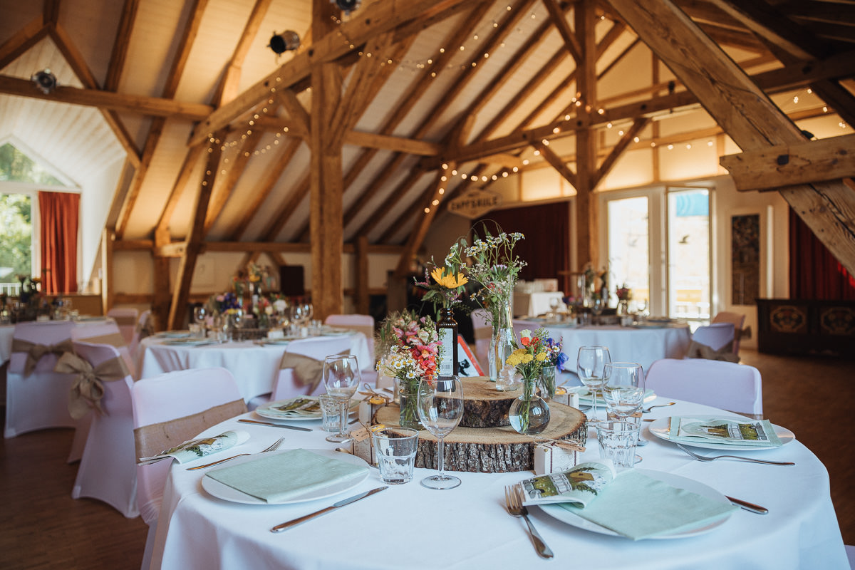 Hochzeit Claudia und Robin gedeckte runde Tische mit Blumen und Holz